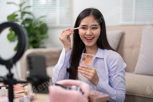 Preview: Beauty broker applying eyeshadow with a brush while showcasing her palette in a live broadcast