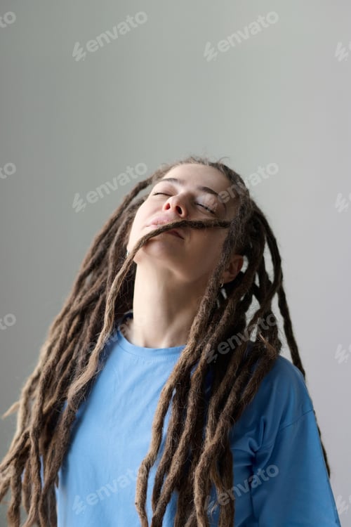Preview: Blissful Woman with Long Dreadlocks and Eyes Closed Standing on White