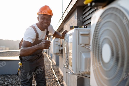 Preview: African man in uniform checking air conditioner on plant