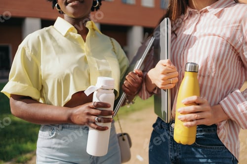 Preview: Close-up view of female students holding laptops and thermal bottles. Back to college.