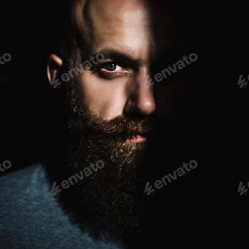 Preview: Close-up portrait of middle aged brutal bearded man with expressive eyes and shadow on half of face