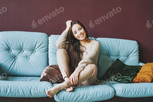 Preview: Beautiful long hair smiling asian girl on sofa on dark background
