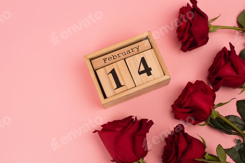 Preview: top view of red roses near calendar with 14 february lettering on pink