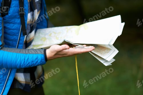 Preview: Cropped view of hiker looking at paper map and compass