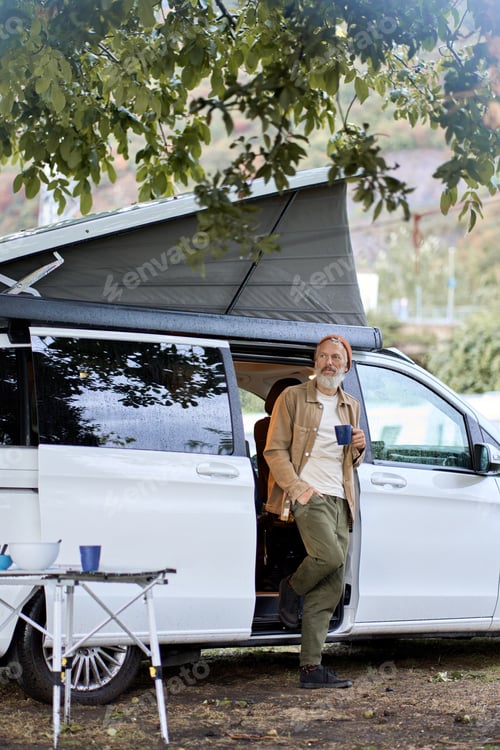 Preview: Active older hipster man standing near rv camper van on vacation trip.