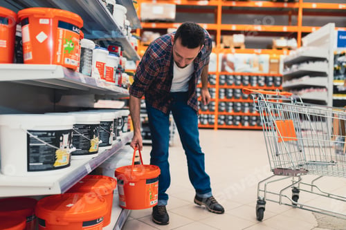 Preview: a buyer in a construction hypermarket chooses a paint for the facade
