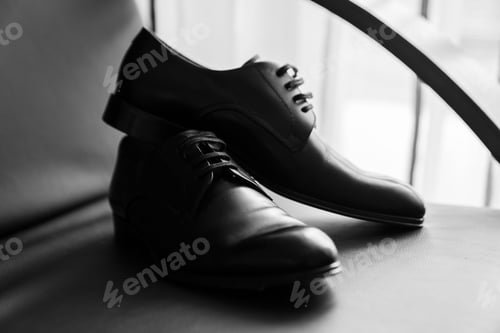 Preview: Grayscale shot of a pair of shoes, resting on a flat surface in a minimalist setting.