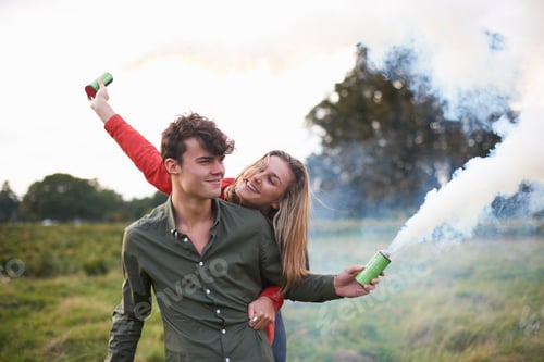 Preview: Young couple letting off smoke flares in field