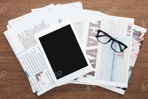 Preview: top view of tablet with blank screen, glasses and newspapers on wooden tabletop