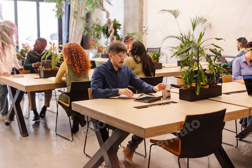 Preview: Focused employee working in modern green office with diverse colleagues