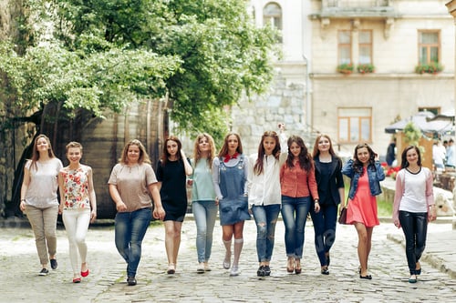 Preview: Group of happy stylish women having fun on background of old european city street