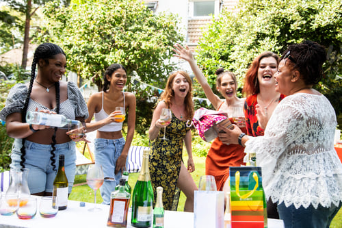 Visualização: Grupo misto de amigas/familiares em uma festa de churrasco no jardim de verão, rindo e se divertindo