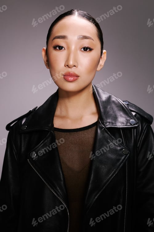 Preview: Fashion, asian woman, black leather jacket, studio portrait, gray background an asian woman poses