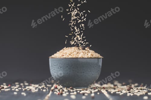 Preview: side view of rice spilling into bowl on black table