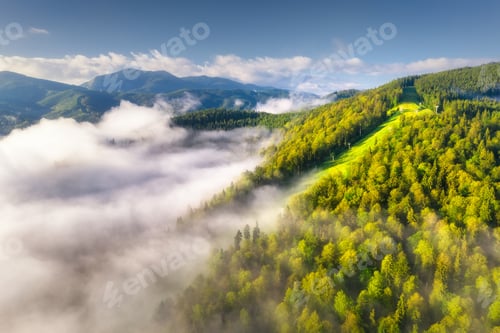 Preview: Mountains in clouds at sunrise in summer. Aerial view