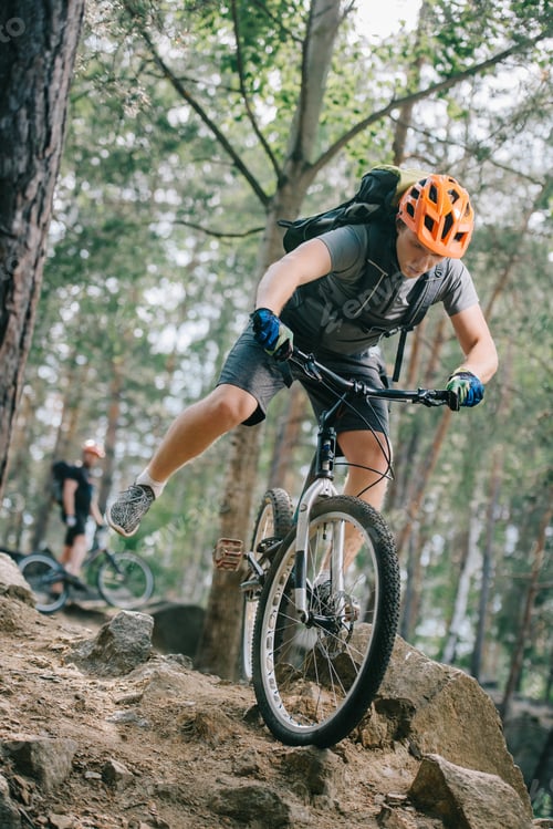 Preview: handsome young trial biker riding at beautiful forest