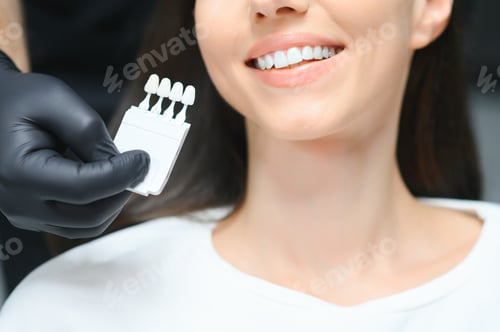 Preview: Dentist checking and selecting color of young woman's teeth