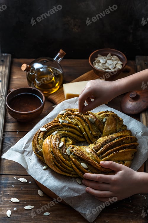 Preview: Small boy put pumpkin seeds on babka brioche wreath