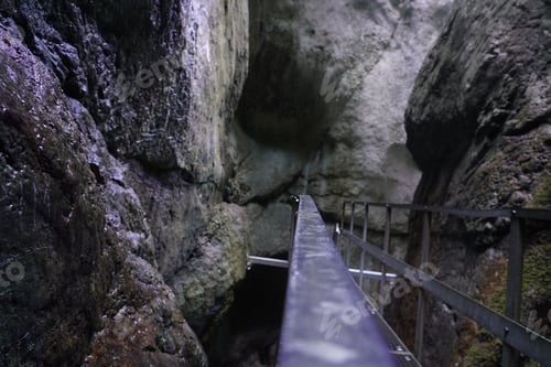 Preview: Metal railing surrounded by massive rocks.