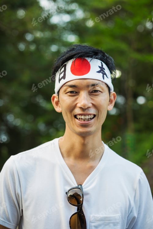 Preview: Portrait of man wearing headband with Japanese flag smiling at camera.