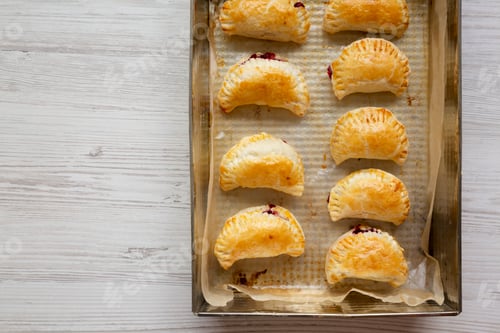 Preview: Homemade Cherry Hand Pies in a baking pan, top view. Flat lay, overhead, from above. Copy space.