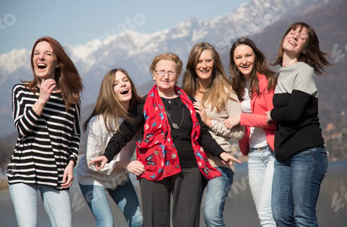 Preview: Grandmother with granddaughters in front of snow capped mountains looking at camera smiling