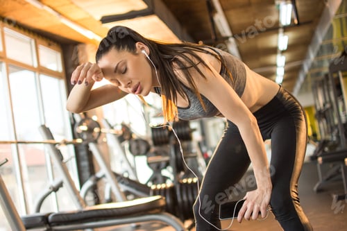Preview: Exhausted young woman taking a break after hard workout in the gym
