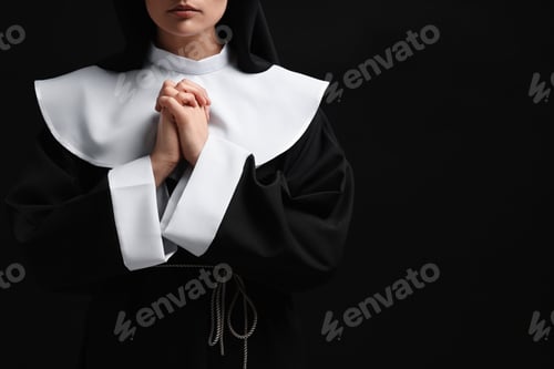 Preview: Nun with clasped hands praying to God on black background, closeup. Space for text
