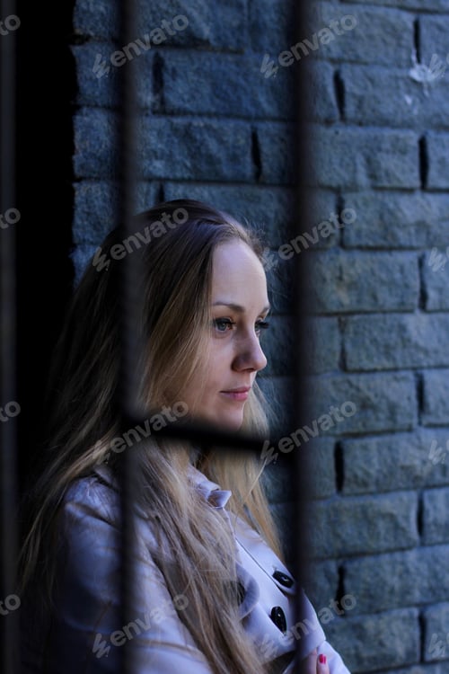 Preview: beautiful woman in a trench coat leaning on the loft brick wall deep in thought. Street photography