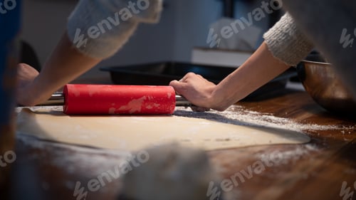 Preview: Low angle view of a woman using rolling pin to roll homemade pastry dough