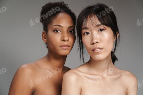 Preview: Portrait of two multinational women posing and looking at camera
