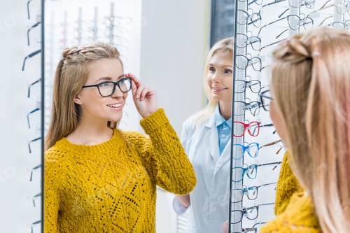 Preview: female optometrist helping client to choose eyeglasses in optics