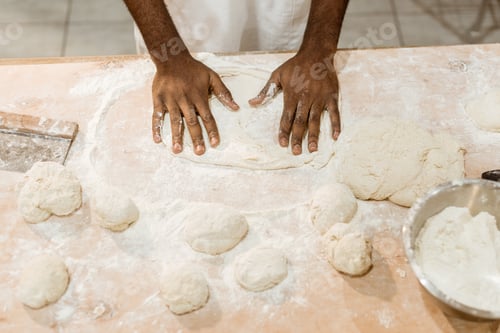 Preview: cropped shot of african american baker kneading dough for pastry on messy table