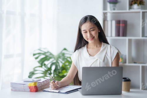Preview: Beautiful Asian businesswoman working on laptop keyboard with document enjoying her work with smilin