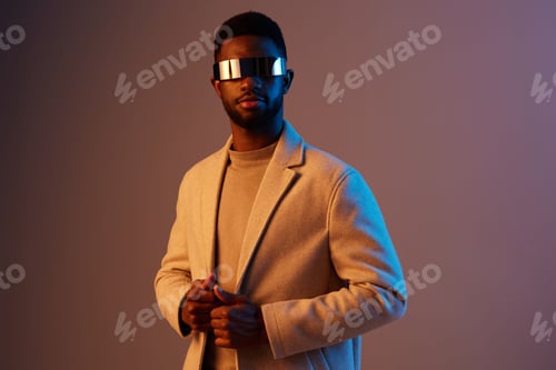 Preview: Stylish African man wearing futuristic sunglasses and a beige coat against a vibrant gradient