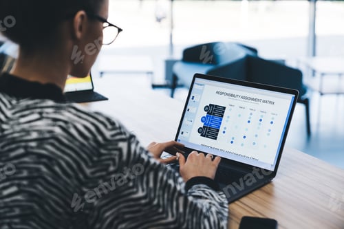 Preview: Crop young female typing on laptop while sitting at table in office