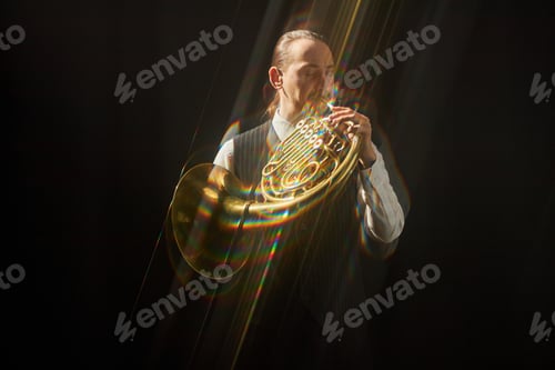 Preview: Male Musician Playing French Horn Performing Music under Spotlight against Black