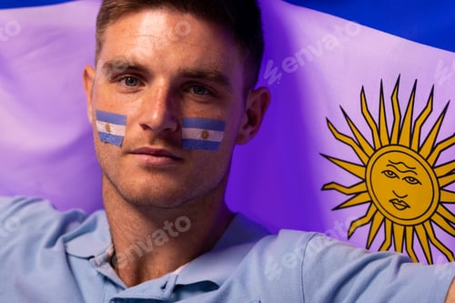 Preview: Portrait of happy caucasian male supporter with flag of argentina over pink lighting