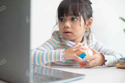 Preview: Asian little cute girl holding Rubik's cube in her hands. Rubik's cube is a game that increases the