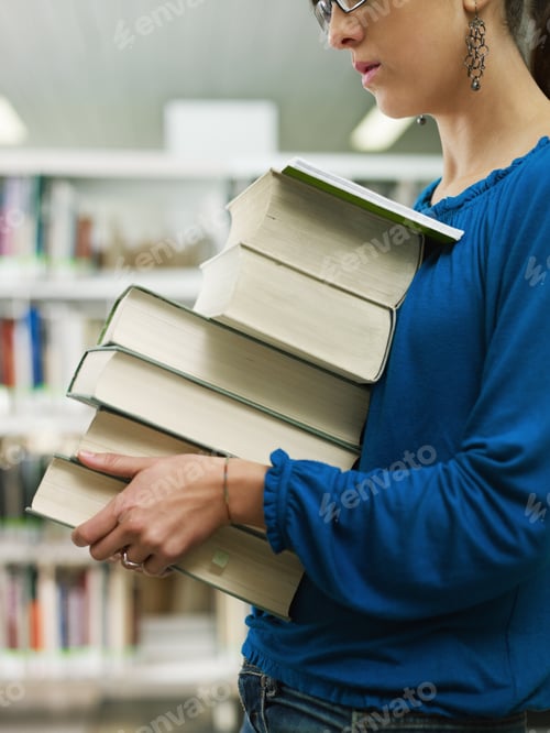 Preview: woman holding pile of books in library