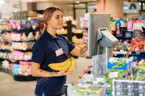 Preview: Grocery store worker weighing bananas at checkout scale