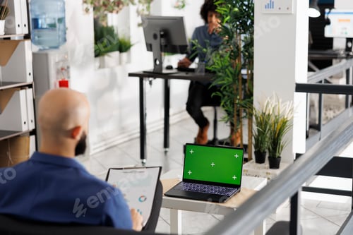 Preview: Businessman using laptop with green screen for data analysis