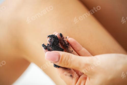 Preview: Woman with beautiful skin on her feet applies anti-cellulite scrub cream on her leg