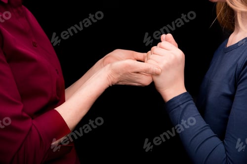 Preview: cropped view of grandchild and grandmother holding hands isolated on black