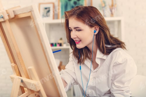 Preview: Young woman enjoying painting in a bright studio with music and creativity