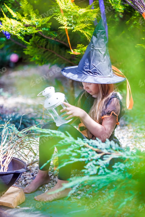 Preview: Adorable little girl in witch costume casting a spell on Halloween. Trick or treat