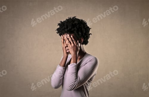 Preview: Pretty black female holding her face with her hands in frustration