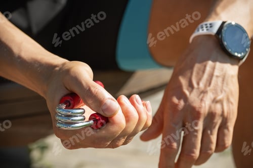 Preview: Sports red metal expander in man's hand.