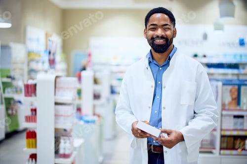 Preview: Smiling Pharmacist Standing in a Pharmacy Holding a Medicine Box