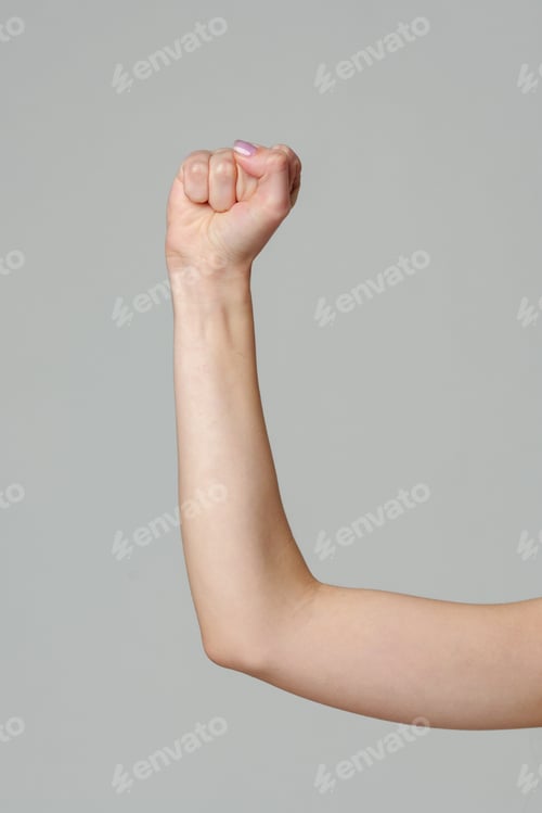 Preview: Female hand with clenched fist on gray background